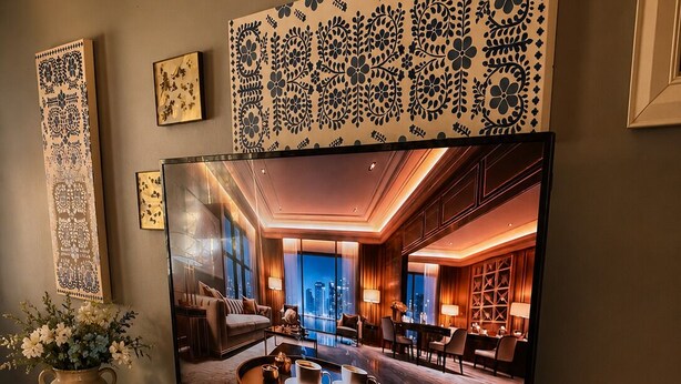 Un salon moderne doté d’un grand téléviseur à écran plat, de meubles en bois et d’œuvres d’art décoratives murales.