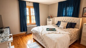 Une chambre à coucher avec un lit, un bureau, un radiateur et une fenêtre avec des rideaux.