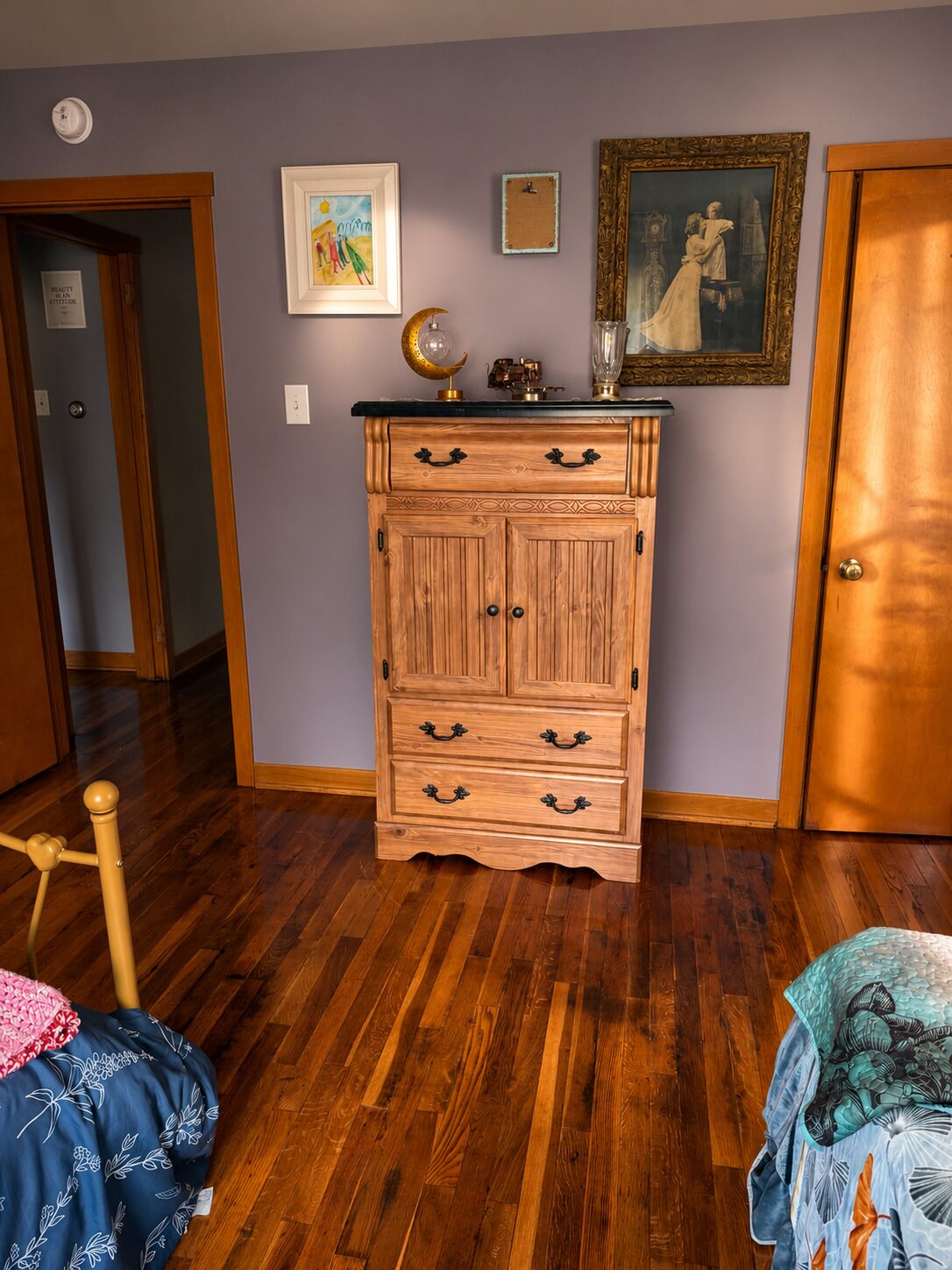 A room with a wooden dresser, a door, and a wall with a framed picture.