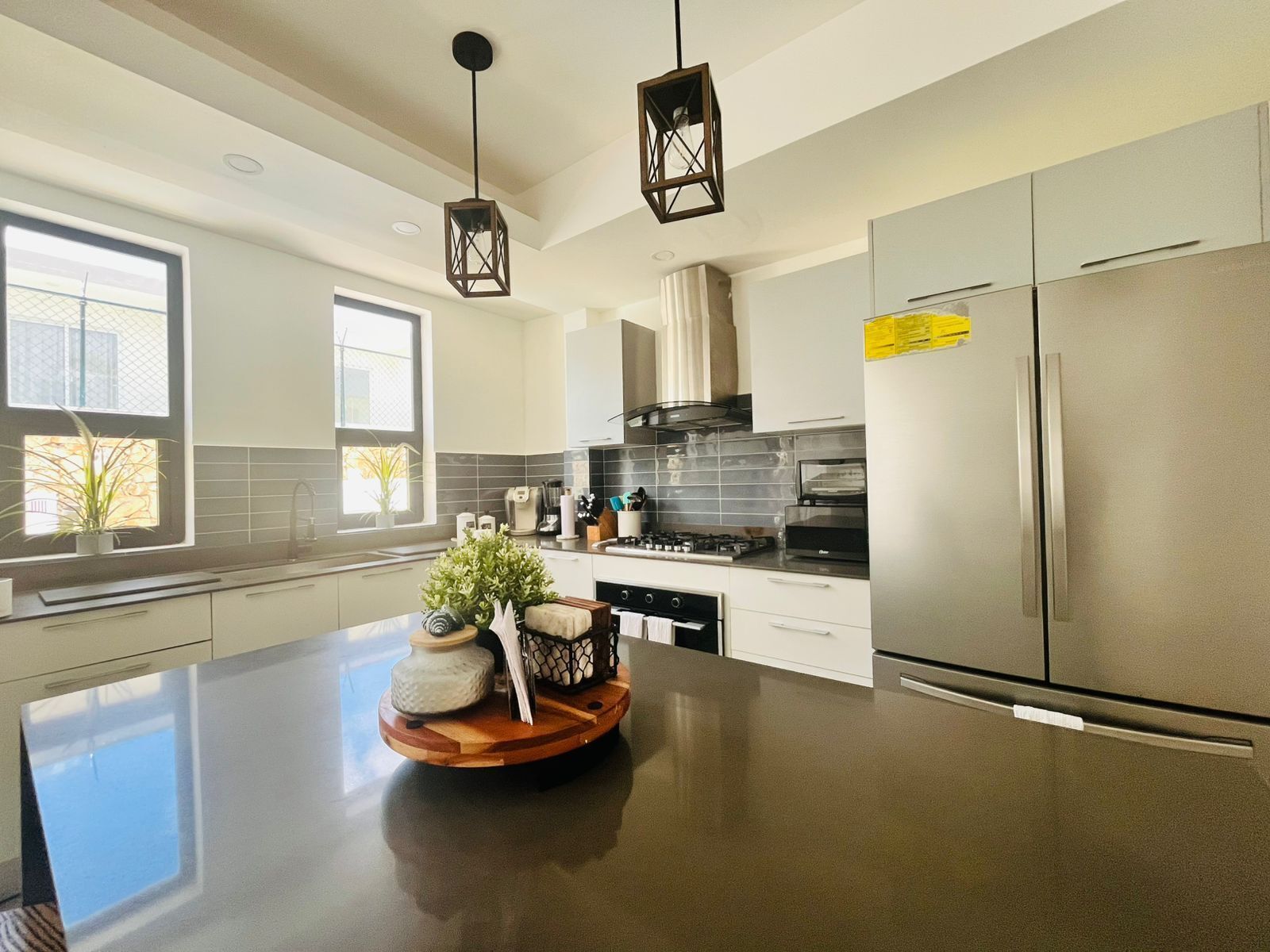 A modern kitchen with a large island, stainless steel appliances, and pendant lighting.