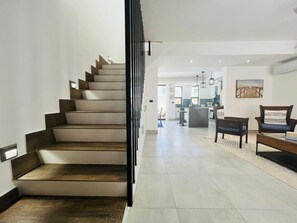 En trappe fører op til et opholdsområde, hvor et køkken ses i baggrunden.
