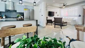 A modern kitchen with a dining area, a living room with a sofa and TV, and a ceiling fan. - 3-bedroom house in tranquil Punta Cana with cool AC breeze (Punta Cana)