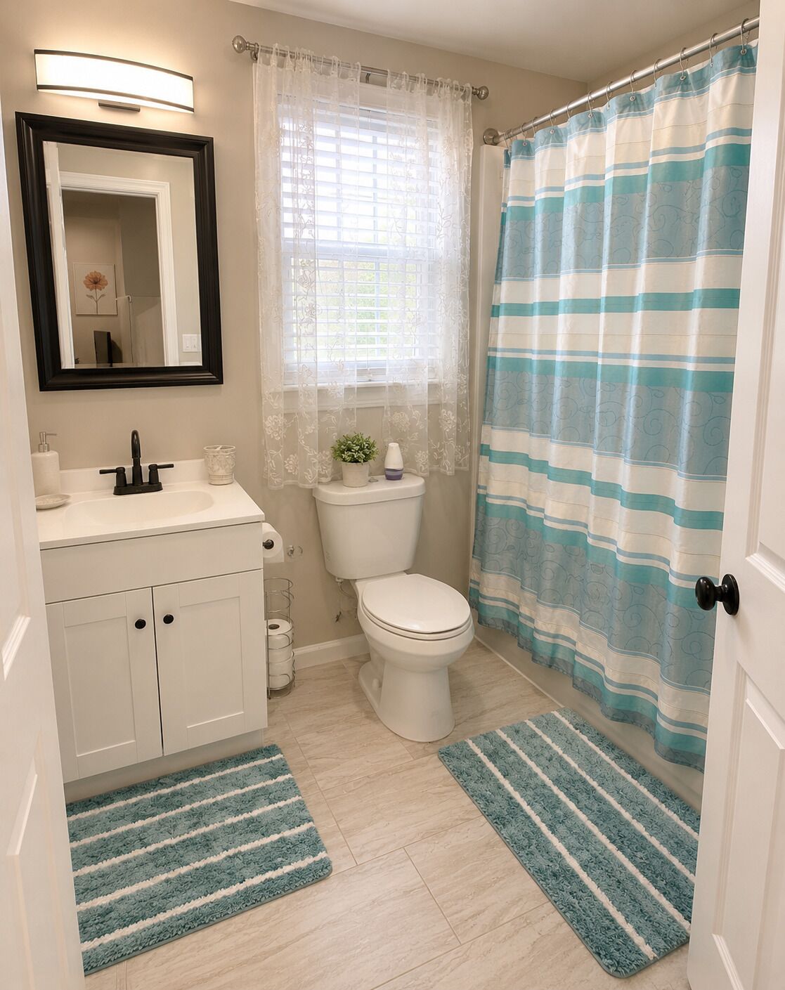 A bathroom with a toilet, sink, mirror, and shower curtain.