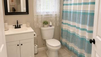 A bathroom with a toilet, sink, mirror, and shower curtain.
