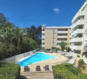 Ein Swimmingpool, umgeben von einem Zaun, mit einem mehrstöckigen Gebäude im Hintergrund.