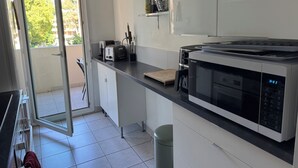 A modern kitchen with a microwave, toaster, and a window to the outside. - Comfortable central apartment, swimming pool, air conditioning, terrace, parking (Hyères)