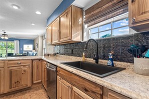 A kitchen with wooden cabinets, a black sink, and a backsplash with a decorative pattern. - Austin's Hideaway Golf-view (Branson)