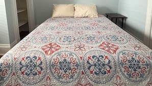 A bedroom with a bed, a nightstand, and a closet with hanging clothes. - Quiet, homey & private 3BR in Swampscott. 7-min walk to beach. (Swampscott)