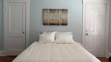 A bedroom with a bed, two doors, and a wall-mounted painting.