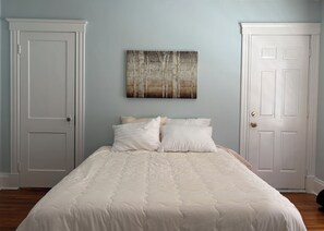 A bedroom with a bed, two doors, and a wall-mounted painting. - Quiet, homey & private 3BR in Swampscott. 7-min walk to beach. (Swampscott)