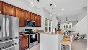 A modern kitchen with stainless steel appliances, wooden cabinets, and pendant lighting. - Tee Time Townhouse-Pool, Garage, close to TPC (Murrells Inlet)