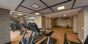 Ein Fitnessstudio mit Laufbändern, Kraftgeräten und einer Spiegelwand.
