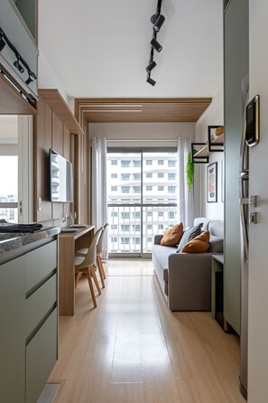 Eine moderne Küche mit Essbereich, einer Couch mit Kissen und einem großen Fenster mit Blick auf die Stadt.