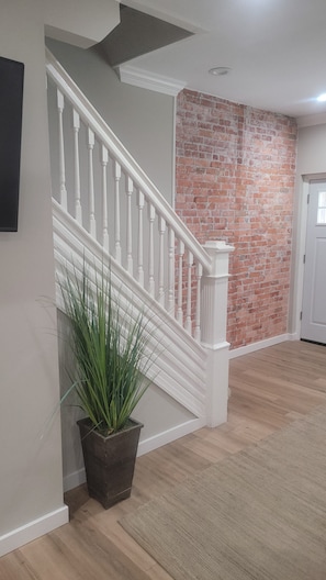 A staircase with white balusters, a brick wall, and a potted plant. -  Shore Getaway. 3-bedroom  house in Fantastic Atlantic City very close Boardwalk (Atlantic City)