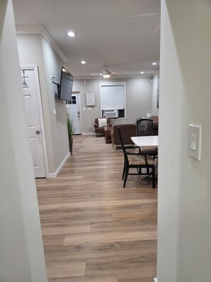 A modern living room with a flat-screen TV, a ceiling fan, and a dining area with a table and chairs. -  Shore Getaway. 3-bedroom  house in Fantastic Atlantic City very close Boardwalk (Atlantic City)