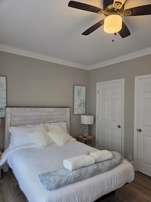 Una camera da letto con un letto, un ventilatore a soffitto, un comodino con una lampada e due porte.