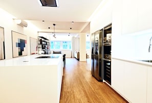 A modern kitchen with white cabinetry, a central island, and a built-in refrigerator. - Stunning 160m² Designer Loft in Estrela | Luxury Living in Lisbon (Lisboa)