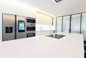 A modern kitchen with built-in appliances, a central island, and a large window with curtains. - Stunning 160m² Designer Loft in Estrela | Luxury Living in Lisbon (Lisboa)
