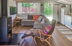 Ein gemütliches Wohnzimmer mit Sofa, Sessel, Kamin und Küchenzeile.
