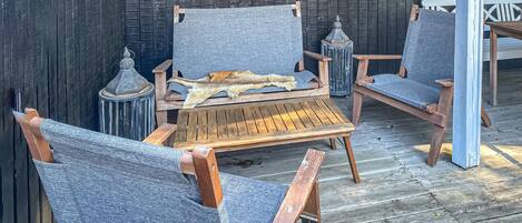 A wooden deck with a rustic outdoor seating area featuring two chairs and a table.