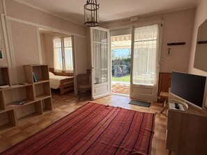 Huoneessa on sänky, tuoli, televisio, kirjahylly ja liukuovet, joista pääsee parvekkeelle.