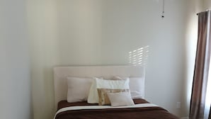A bedroom with a bed, a bedside table, a ceiling fan, and a window with curtains. - Cozy 2 bedrooms in Evans for Travelling Medical Professionals (Evans)