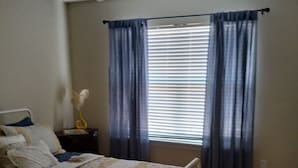 A bedroom with a bed, a nightstand, a ceiling fan, and a window with curtains. - Cozy 2 bedrooms in Evans for Travelling Medical Professionals (Evans)