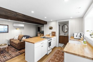 Une cuisine compacte avec des meubles blancs, un plan de travail en bois et un four encastré.