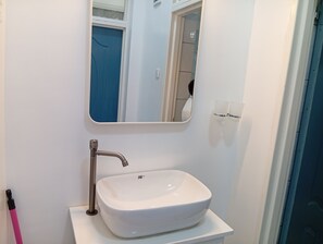 A bathroom with a white sink, a mirror, and a blue door. - 3 minutes walk to Kigali Rwanda Airport, welcome 🤗 (Kigali)