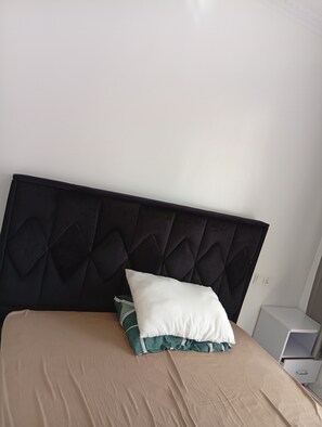 A bed with a dark headboard, a white pillow, and a green pillow with a striped pattern. - 3 minutes walk to Kigali Rwanda Airport, welcome 🤗 (Kigali)