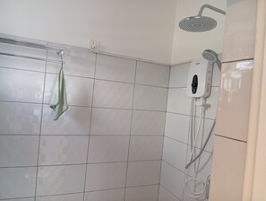 Un área de ducha con cabezal de ducha de mano y otro cabezal de ducha instalado en la pared.