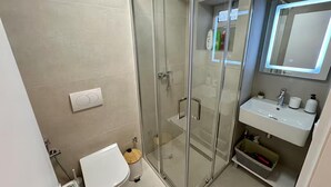A bathroom with a glass shower enclosure, a toilet, and a sink with a mirror above it. - Dajti National Park House, Sleeps 7 With Aircon (Tirana)