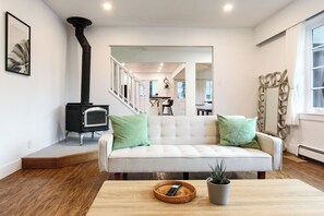 Ein Wohnzimmer mit einer Couch, einem Kamin, einem Essbereich und einer Treppe.