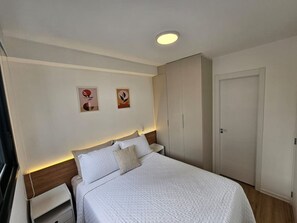 Ein Schlafzimmer mit einem Bett, Nachttischen, einem Kleiderschrank und zwei Wandbildern.