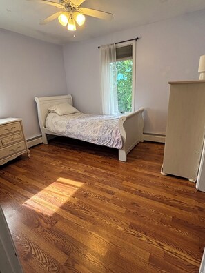 A bedroom with a bed, dresser, and ceiling fan.