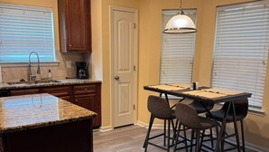 A kitchen with a central island, wooden cabinets, a dining table with chairs, and a pendant light. - 4-BDRM • FIFA Stadium • Airport • Downtown ATL • Six Flags • Wolf Creek Concerts (Atlanta)