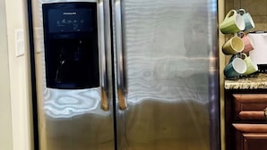 A stainless steel refrigerator with a water dispenser, double doors, and wooden cabinets in the background. - 4-BDRM • FIFA Stadium • Airport • Downtown ATL • Six Flags • Wolf Creek Concerts (Atlanta)