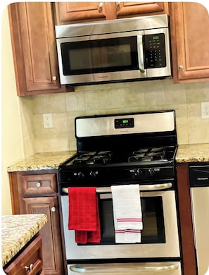 A kitchen with a stainless steel microwave, oven, and stove, wooden cabinets, and a granite countertop. - 4-BDRM • FIFA Stadium • Airport • Downtown ATL • Six Flags • Wolf Creek Concerts (Atlanta)