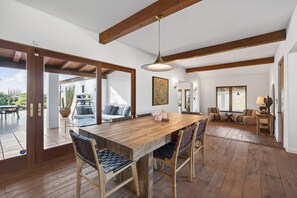 A spacious dining area with a wooden table and chairs, a pendant light, and a view of the patio.