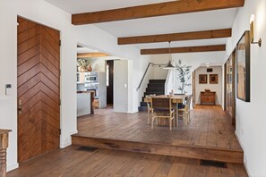 A wooden-floored interior with a dining area, staircase, and kitchen visible in the background.