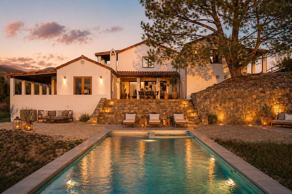 A modern house with a swimming pool, stone steps, and outdoor seating.