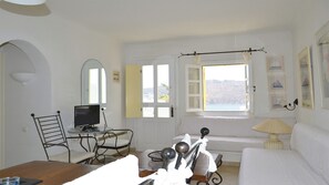 Ein Zimmer mit einem Bett, einem Schreibtisch mit Computer, einem Stuhl, einem Fenster mit Vorhängen und einer Lampe.