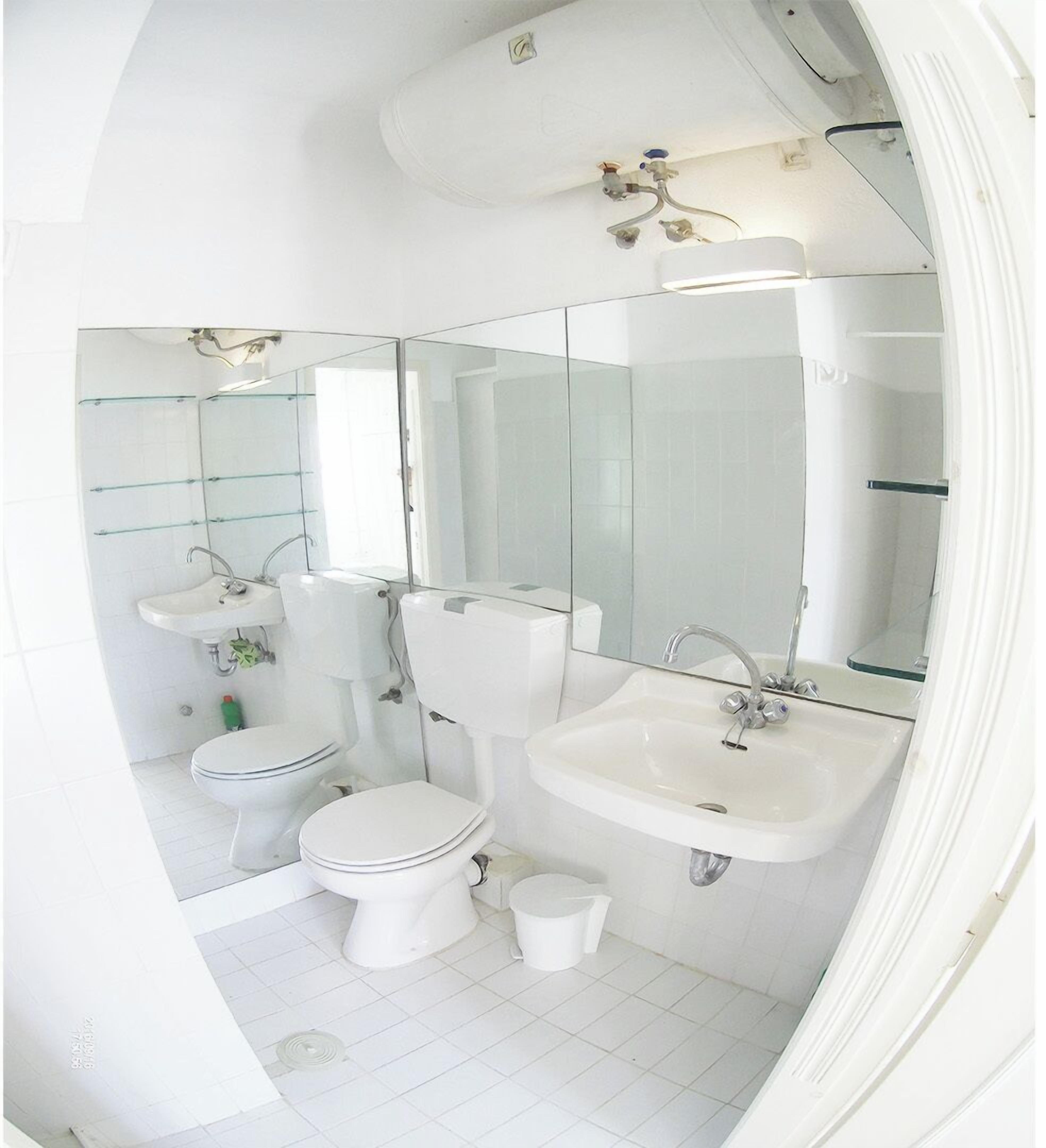 Une salle de bain avec des toilettes, un lavabo et un miroir.