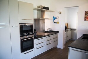 A modern kitchen with stainless steel appliances, white cabinetry, and a black countertop. - VILLA GIRELLES 5 Bed Room (PIETROSELLA)