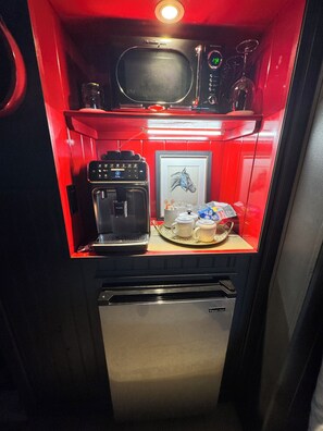 Une petite cuisine équipée avec une machine à café, un four à micro-ondes et un petit réfrigérateur.