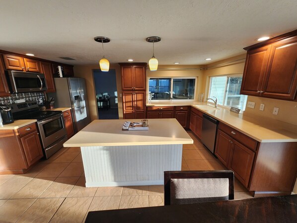 A modern kitchen with wooden cabinets, stainless steel appliances, and a large island. - Waterfront west coast home (Holiday)
