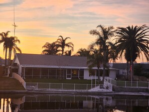 A house with a sloped roof, a fenced yard, and a body of water in front. - Waterfront west coast home (Holiday)