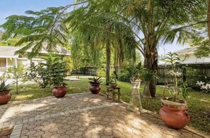 Ein Garten mit Topfpflanzen, einem gewebten Korb und einer Terrassenfläche.