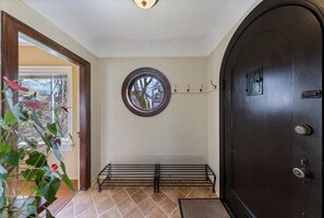 A hallway with a dark wooden door, a round window, and a bench.