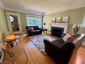 Una sala de estar con chimenea, un sofá, una mesa de centro y un sillón.